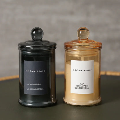 Aroma Home candles, one black and one with a clear lid, on a dark surface with a gray background.