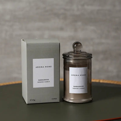 Aroma Home sandalwood scented candle and packaging on a gray surface with a neutral background