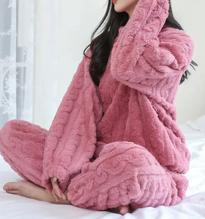 Person wearing a pink fluffy robe sitting on a bed.