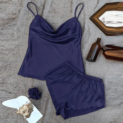 Navy blue satin camisole and shorts set on a textured surface with decorative items.